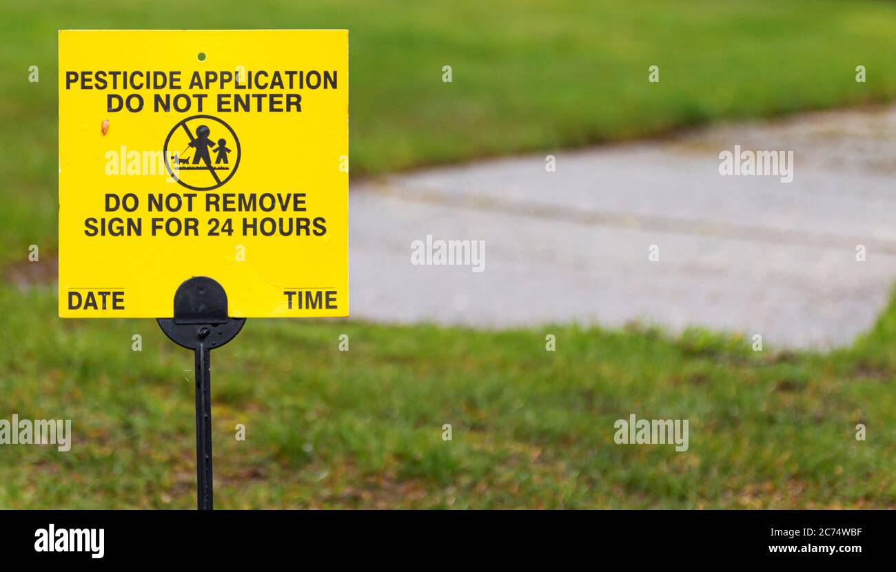 Ein gelbes Schild Platz auf einem Wohnrasen liest Pestizid Anwendung, nicht für 24 Stunden eingeben. Stockfoto