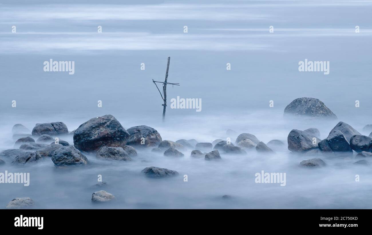 Einsames Kreuz im Nebel in einem Haufen nasser Steine. Mirissa. Sri Lanka Stockfoto
