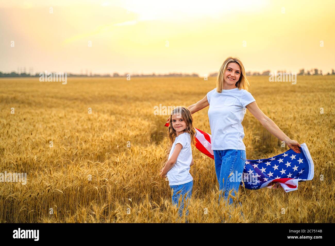 Mutter und Tochter mit amerikanischer Flagge in einem schönen Weizenfeld Stockfoto