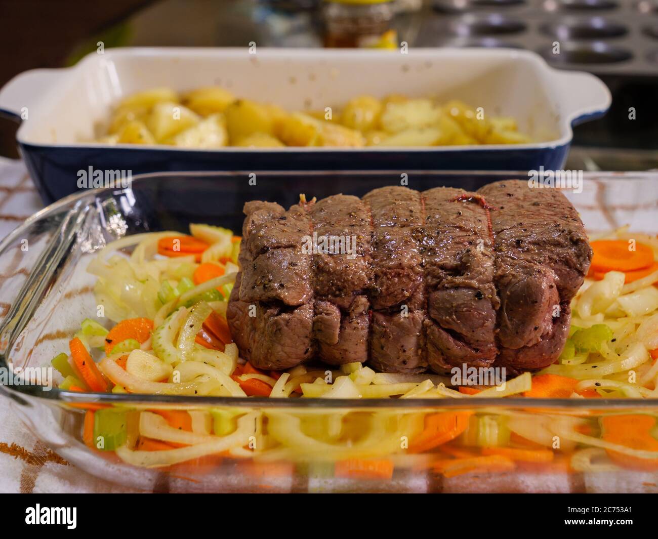 Ein traditionelles Sonntagsbraten mit einem Rinderbraten und Kartoffeln auf einer rustikalen karierten Tischdecke in einer heimischen Küche Stockfoto