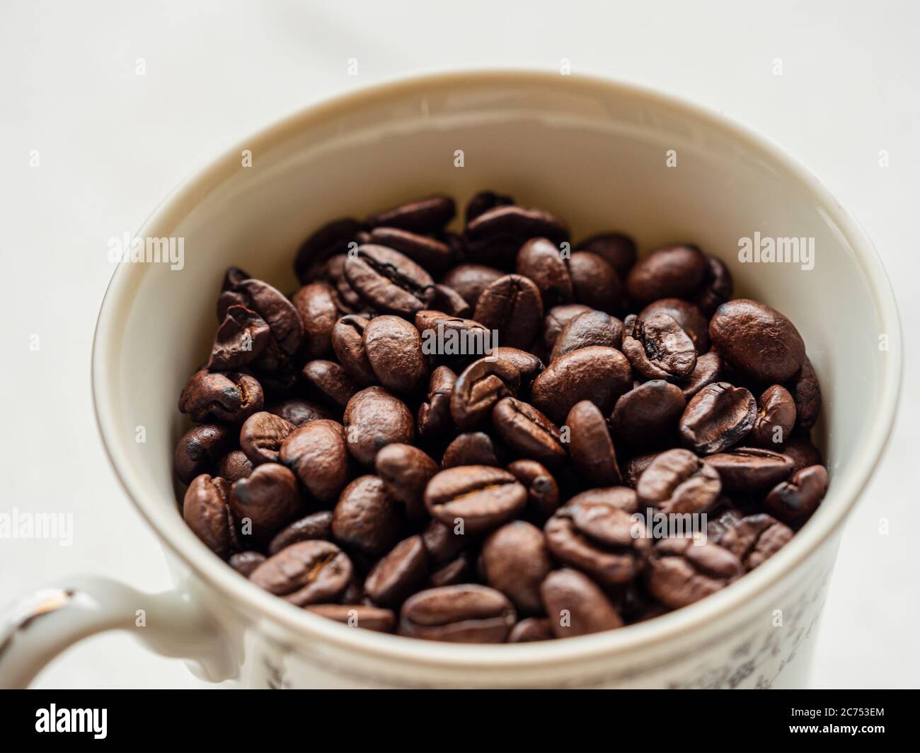 Makro-Nahaufnahme von gerösteten Kaffeebohnen in einer feinen porzellan weißen Porzellanbecher vor weißem Hintergrund Stockfoto