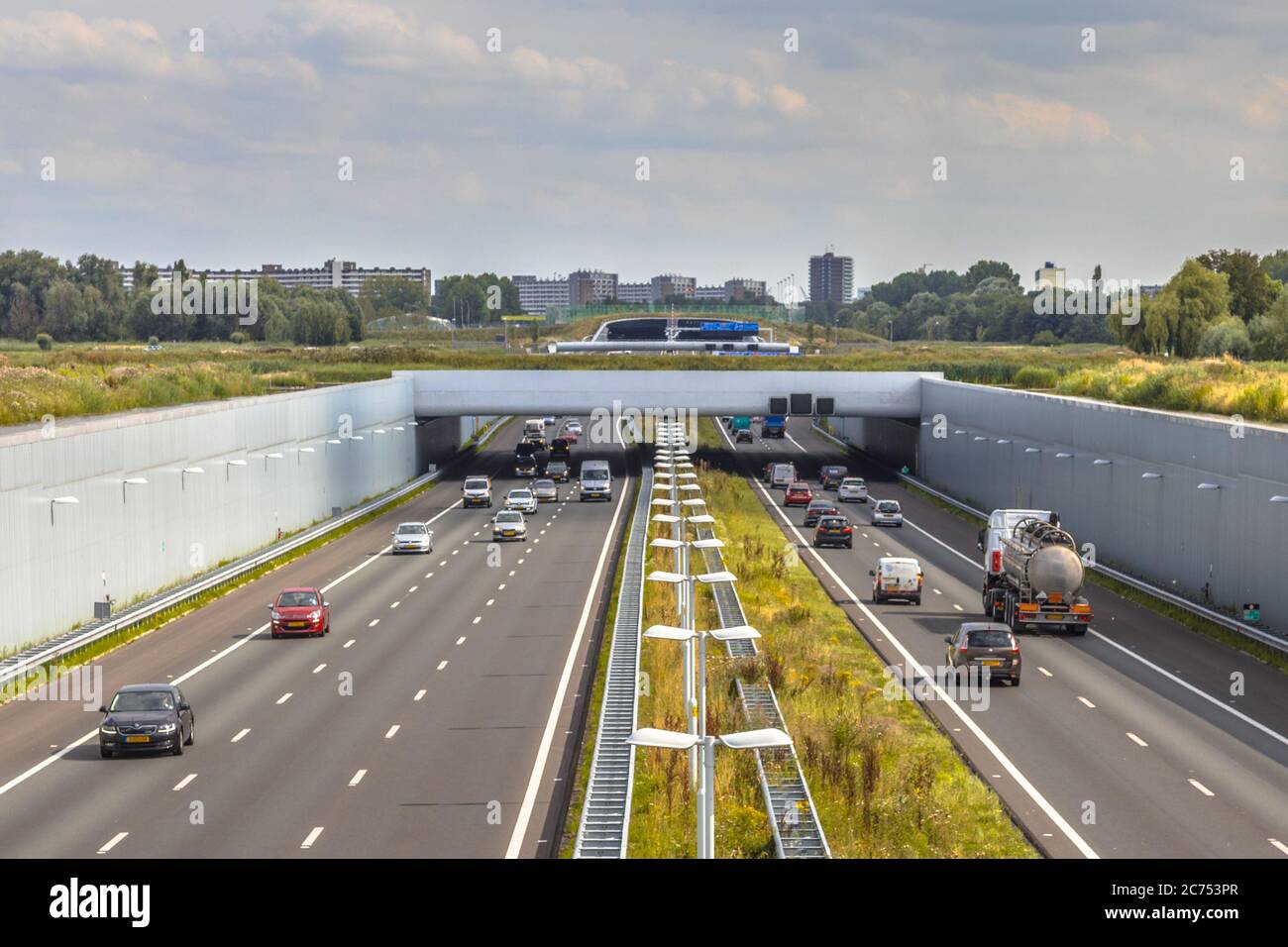 Nachmittags Verkehr auf der autobahn a4 in der Nähe von Den Haag Randstad. Autobahnkreuzung Aquadukt Tunnel mit Stadtgebiet von Rotterdam im Hintergrund, Niederlande. Stockfoto