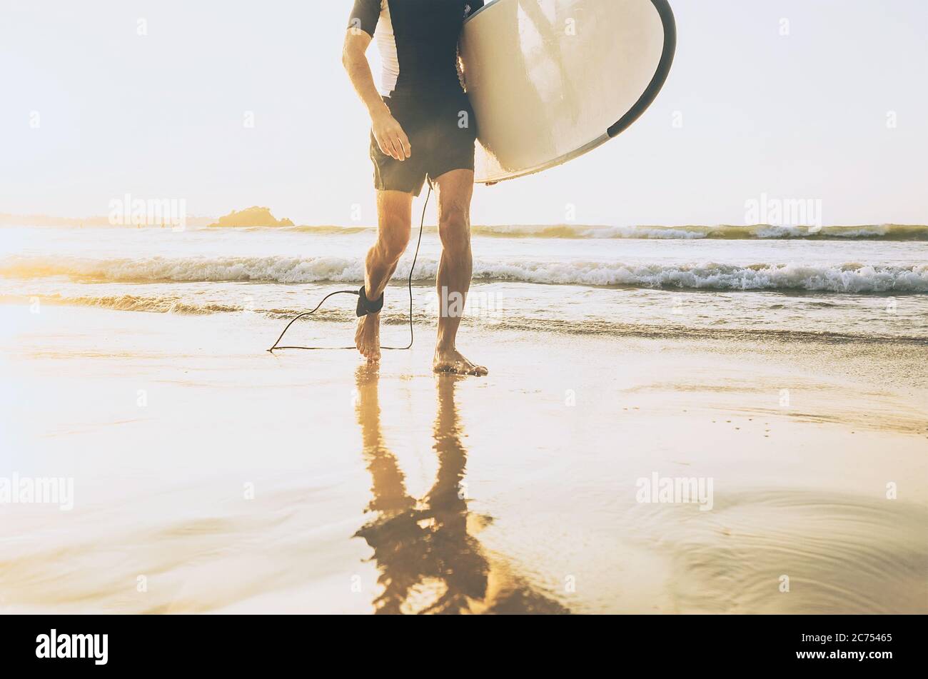 Surfer Mann mit langen Board zu Fuß aus dem Meer Wellen auf sonnigen Strand. Konzept für aktive Urlaubszeit. Stockfoto