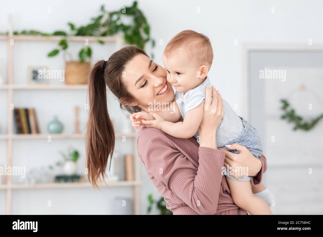 Glück Der Mutterschaft. Freudige Mutter hält niedlichen Kleinkind Baby auf ihren Händen Stockfoto