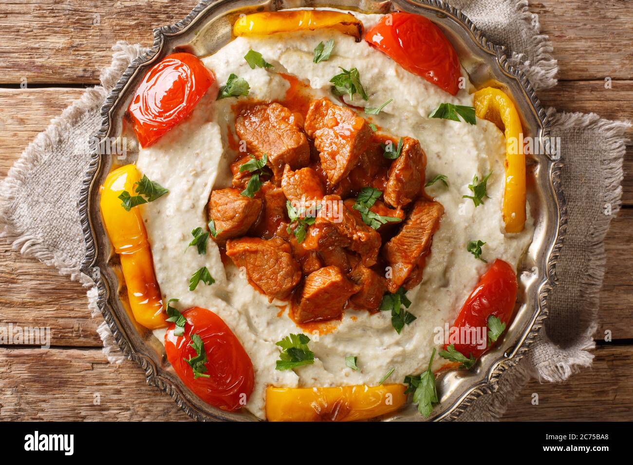 Ali Nazik Kebab ist zartes, saftiges Lamm, das auf einem Bett aus heiß gerösteter Aubergine serviert wird, das mit schlichtem Joghurt in der Nähe auf dem Teller auf dem Tisch gepeitscht wird. hori Stockfoto