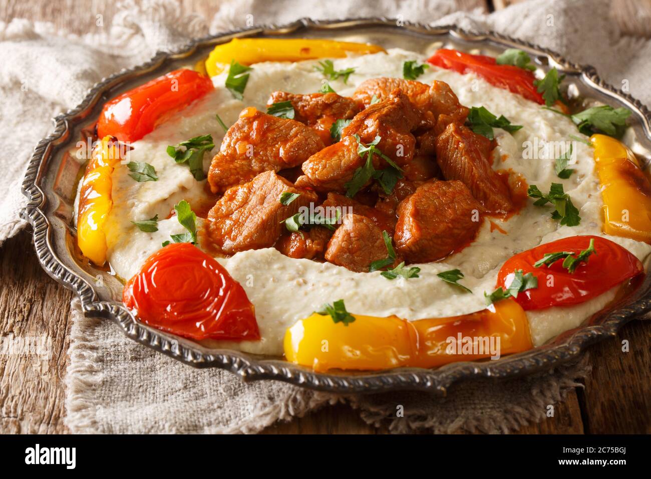 Ali Nazik Kebab ist kleine Scheiben zartes Lamm in roter, dicker Pfeffersauce mit zermahlenen duftenden Auberginen in der Nähe auf dem Teller auf dem Tisch. Horizontal Stockfoto