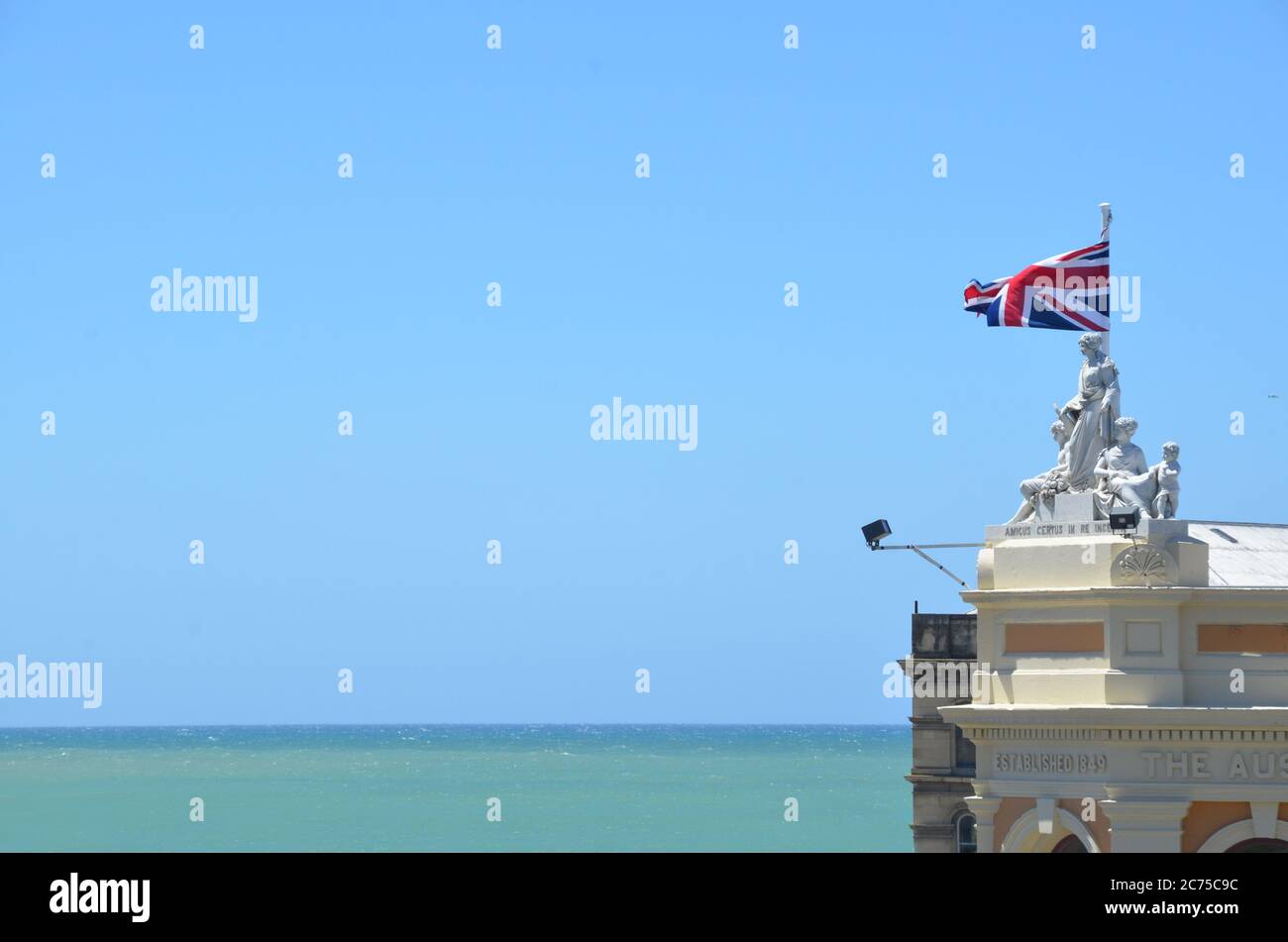 Dachstatuen auf dem Oamaru Steingebäude mit neuseeländischer Flagge bei Oamaru. Stockfoto