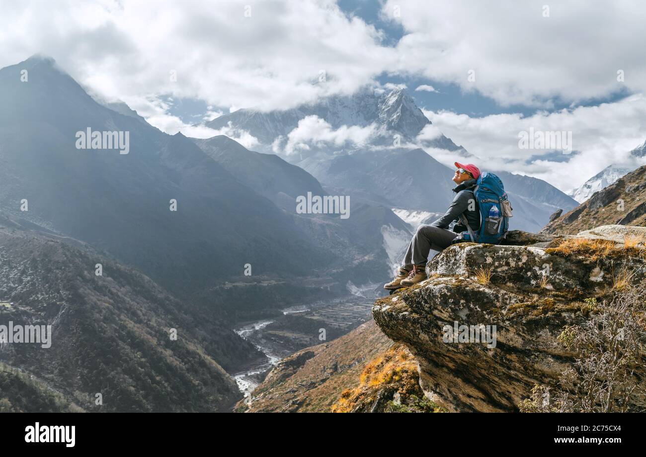 Junge Wandererin Backpacker sitzt am Klippenrand und genießt die Aussicht auf die Berggipfel während der Everest Base Camp (EBC) Trekking Route in der Nähe von Phortse, N Stockfoto