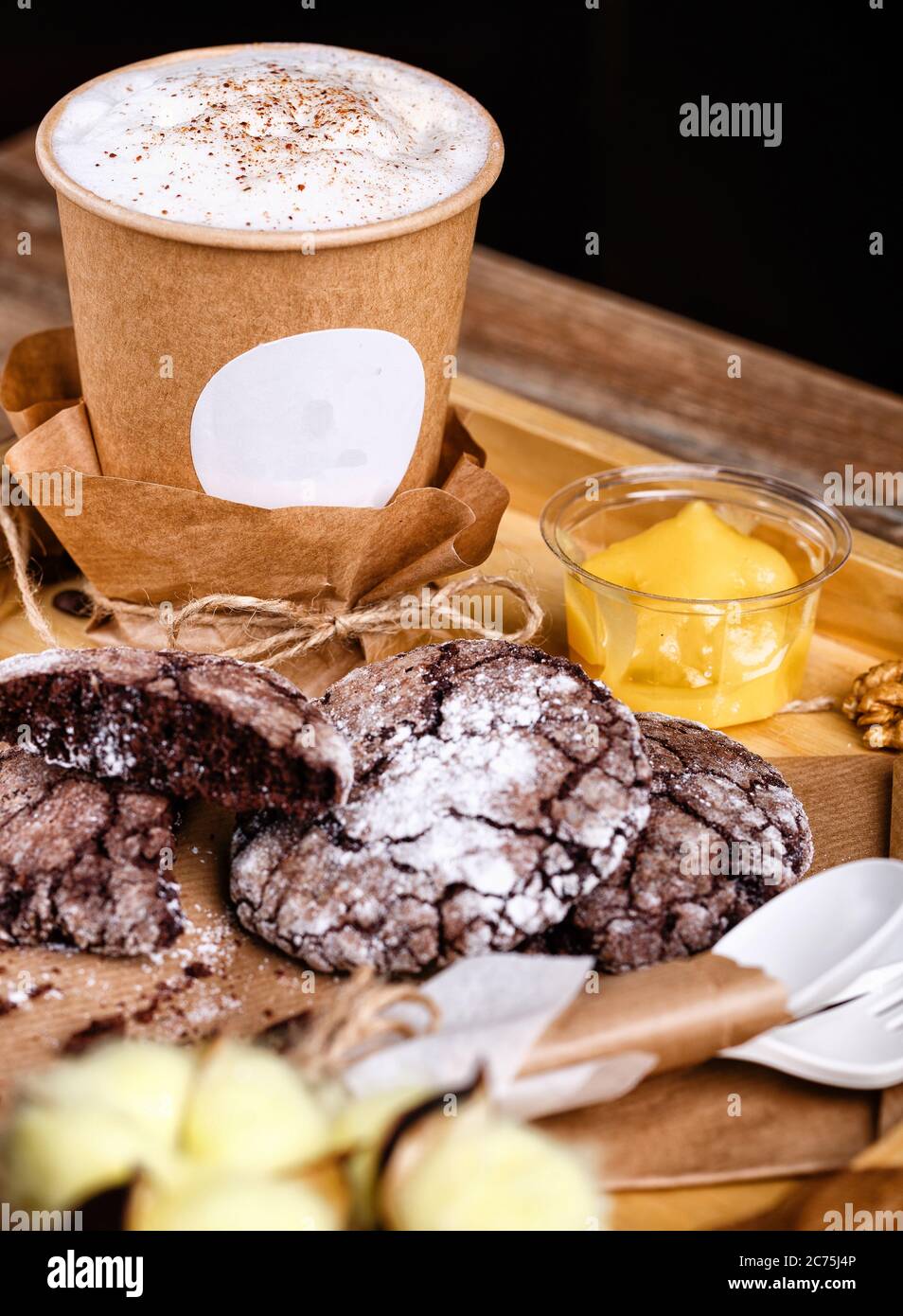 Zimtkaffee in einer Pappbecher mit Keksen auf einem Holztablett Stockfoto