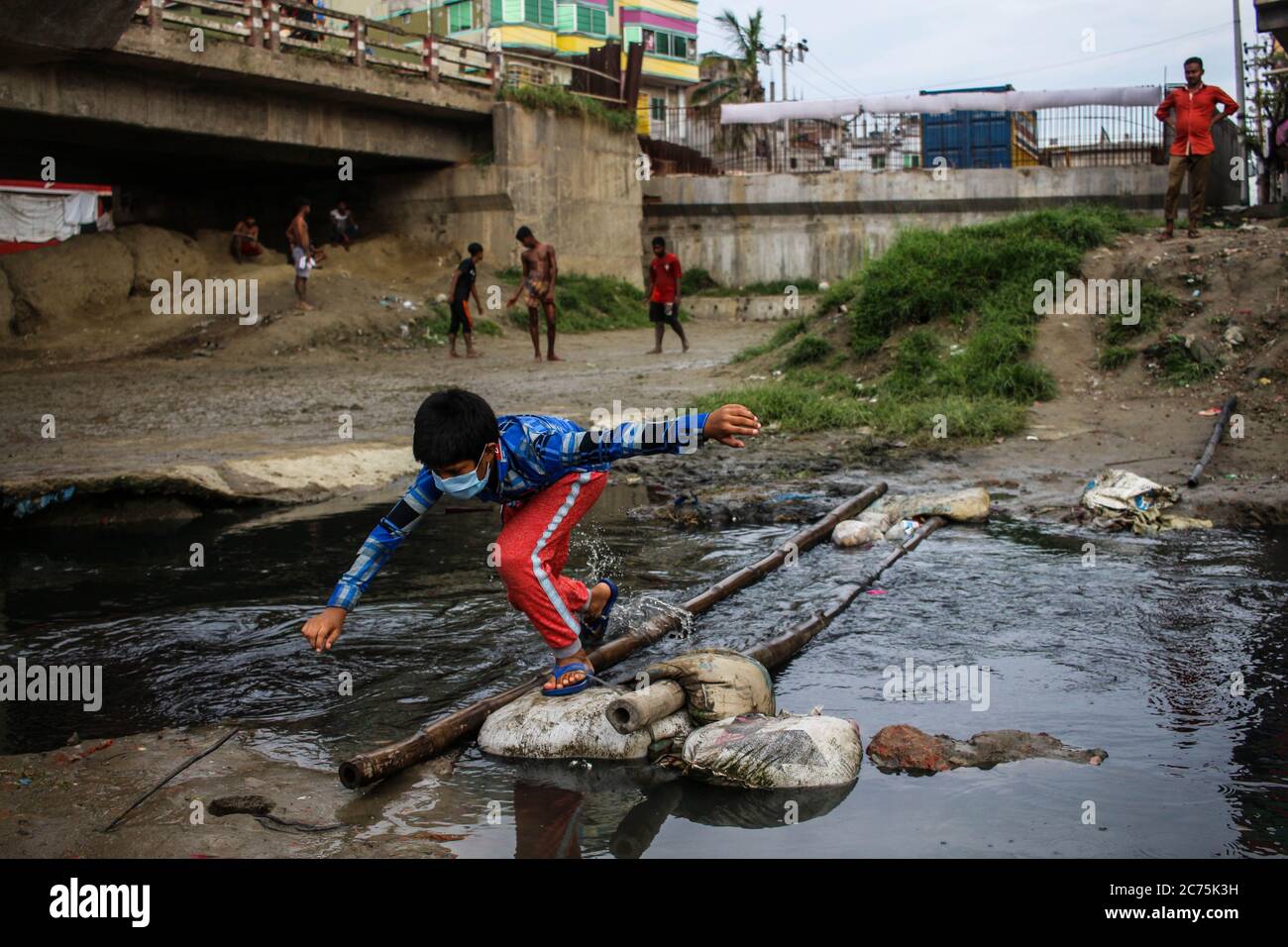 Dhaka, Dhaka, Bangladesch. Juli 2020. Ein Kind rutscht während des Ausbruchs der COVID-19 in Dhaka über eine Bambusbrücke auf dem verschmutzten Shubhabada-Kanal in Begunbari, Süd-Keranigonj. 14. Juli 2020. Dhaka, Bangladesch. Kredit: Nayem Shaan/ZUMA Wire/Alamy Live Nachrichten Stockfoto