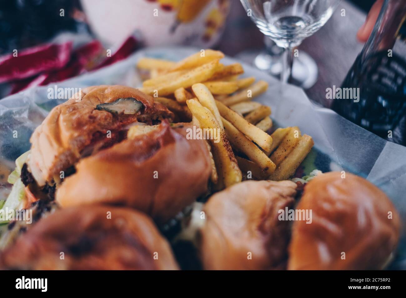 Nahaufnahme von in Scheiben geschnittenen Hamburgern und pommes auf Pergamentpapier. Selektiver Fokus. Stockfoto