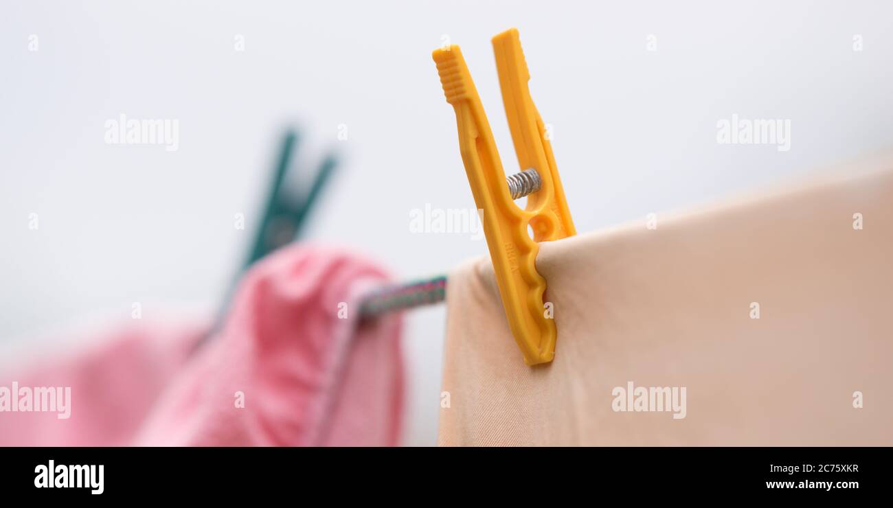 Die Kleidung wird an einem Seil mit Plastikkleider getrocknet. Nahaufnahme, schöner selektiver Fokus. Stockfoto