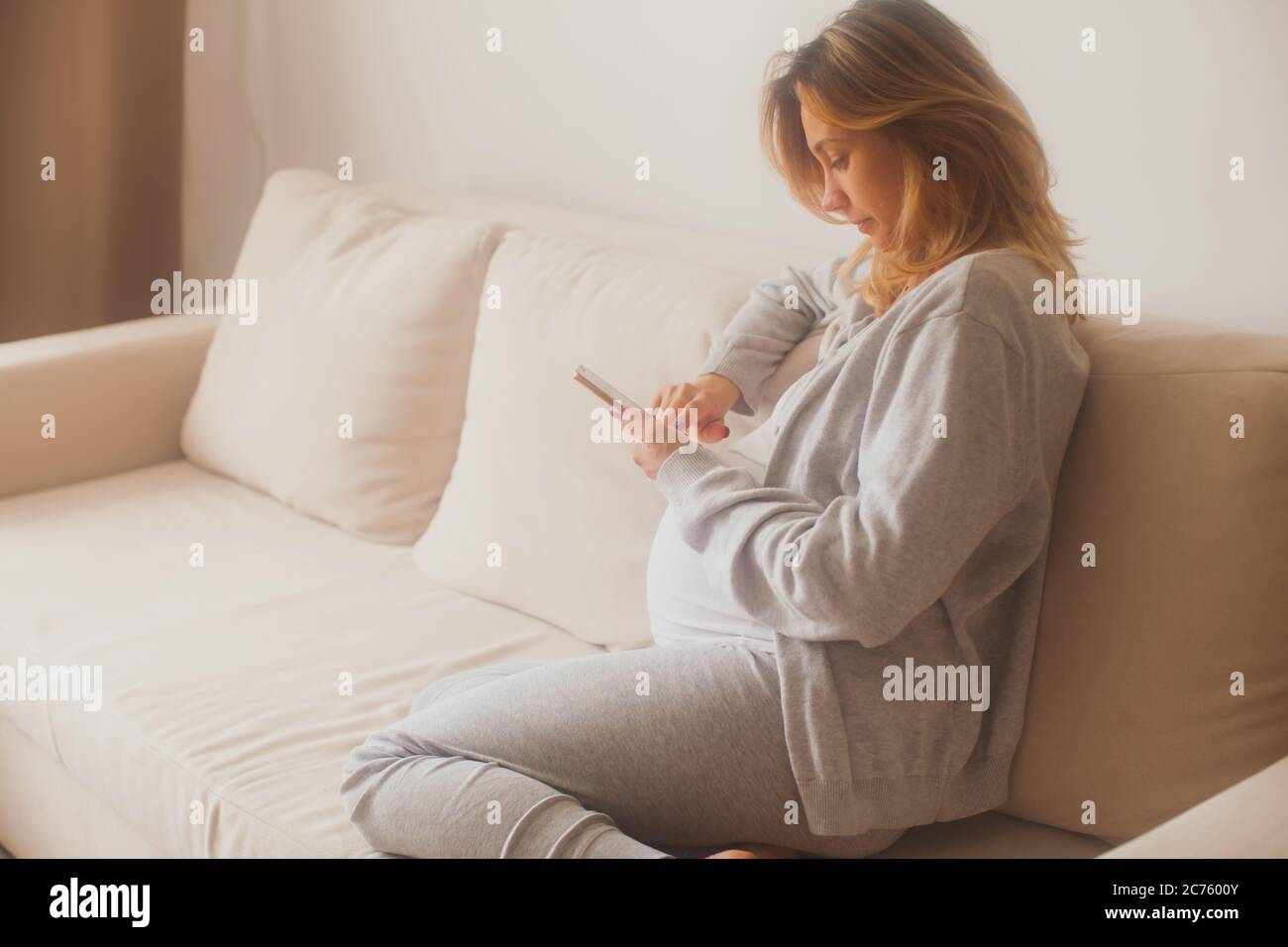 Schwangere Frau Zählen Kontraktionen mit Smartphone-App Stockfoto
