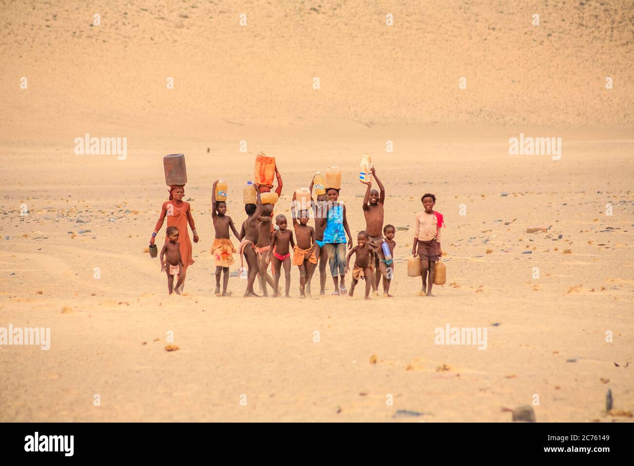Frau Himba und Kinder arbeiten, die Wasser in ein Dorf der Himba Volk in der Kunene Region, Namibia, im Südwesten von Afrika Stockfoto