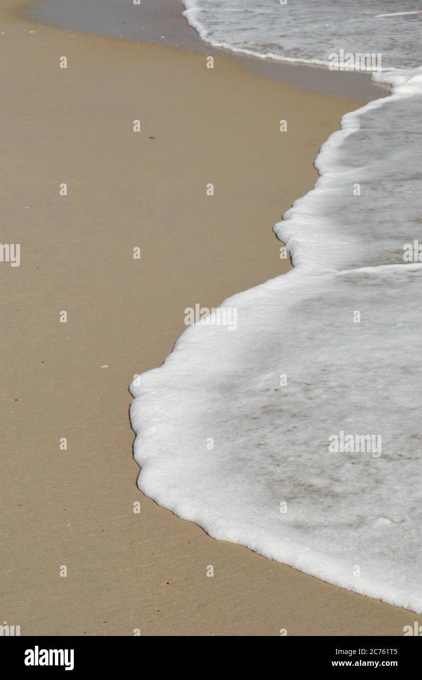 Das Meer liegt an einem Sandstrand mit viel Platz für Kopien Stockfoto