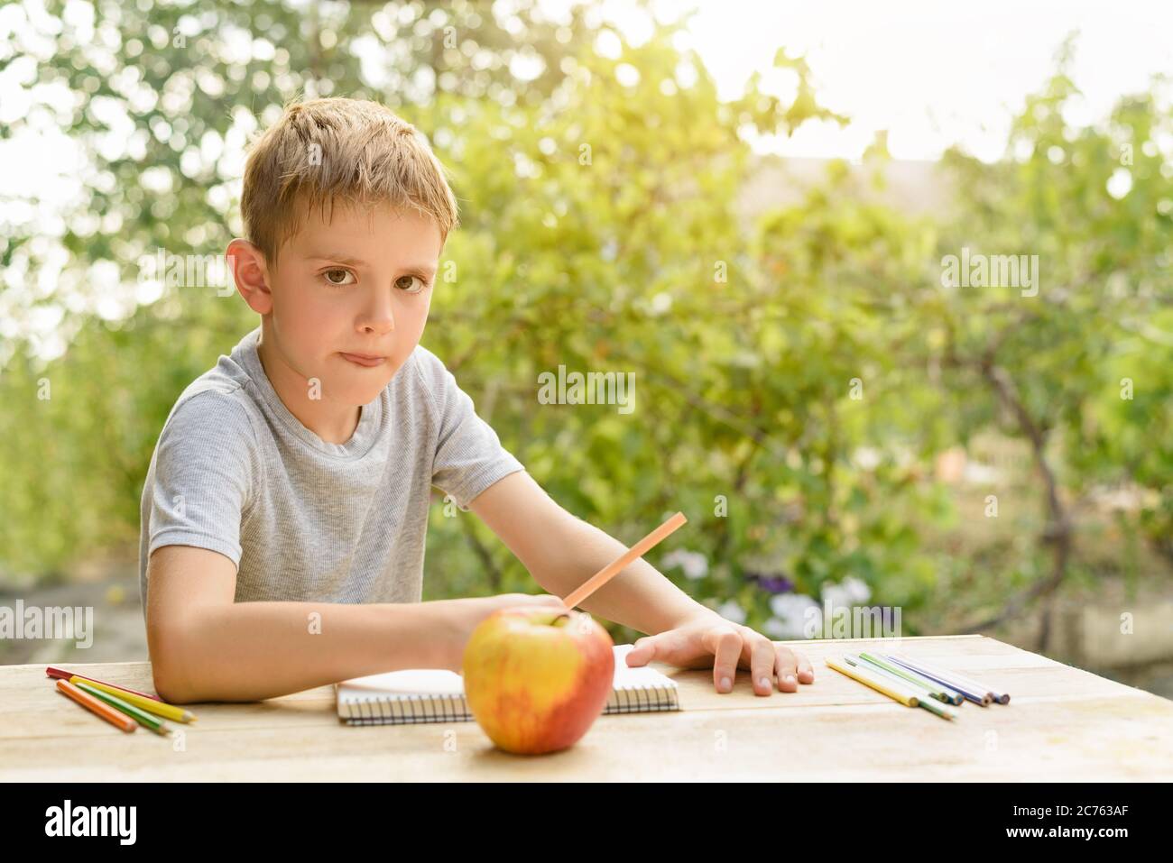 Niedlichen Jungen zeichnet mit Bleistiften Stillleben. Open Air. Garten im Hintergrund. Kreatives Konzept. Stockfoto