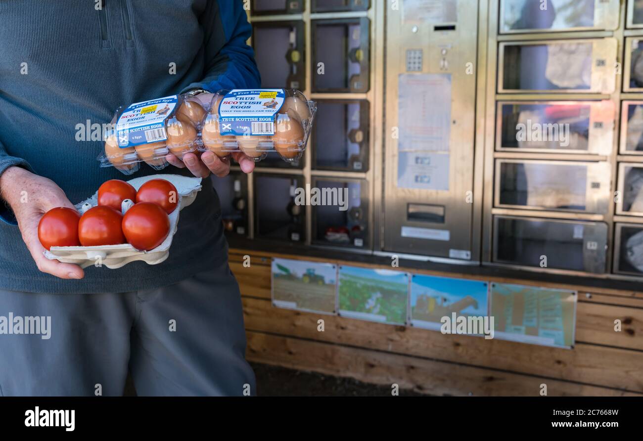 Mann mit Freilandei und Tomaten aus dem Automaten im Veg Shed, Athelstaneford Hauptfarm, East Lothian, Schottland, Großbritannien Stockfoto