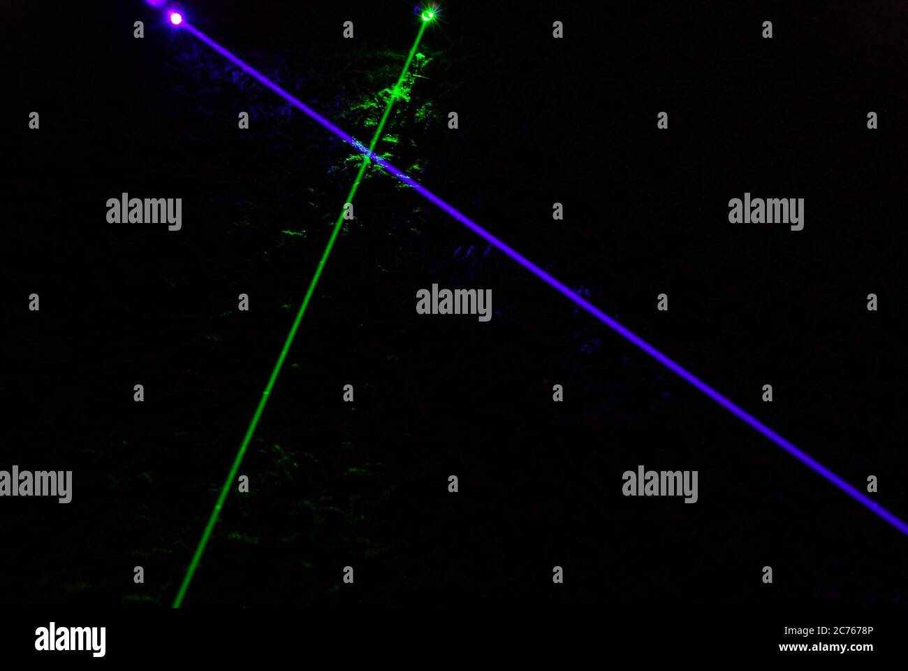 Grüner und violetter oder violetter Laserstrahl, Überquerung, Laserstrahlen, Laser, die sich kreuzen, abfangen, überlappen, überlappen Stockfoto