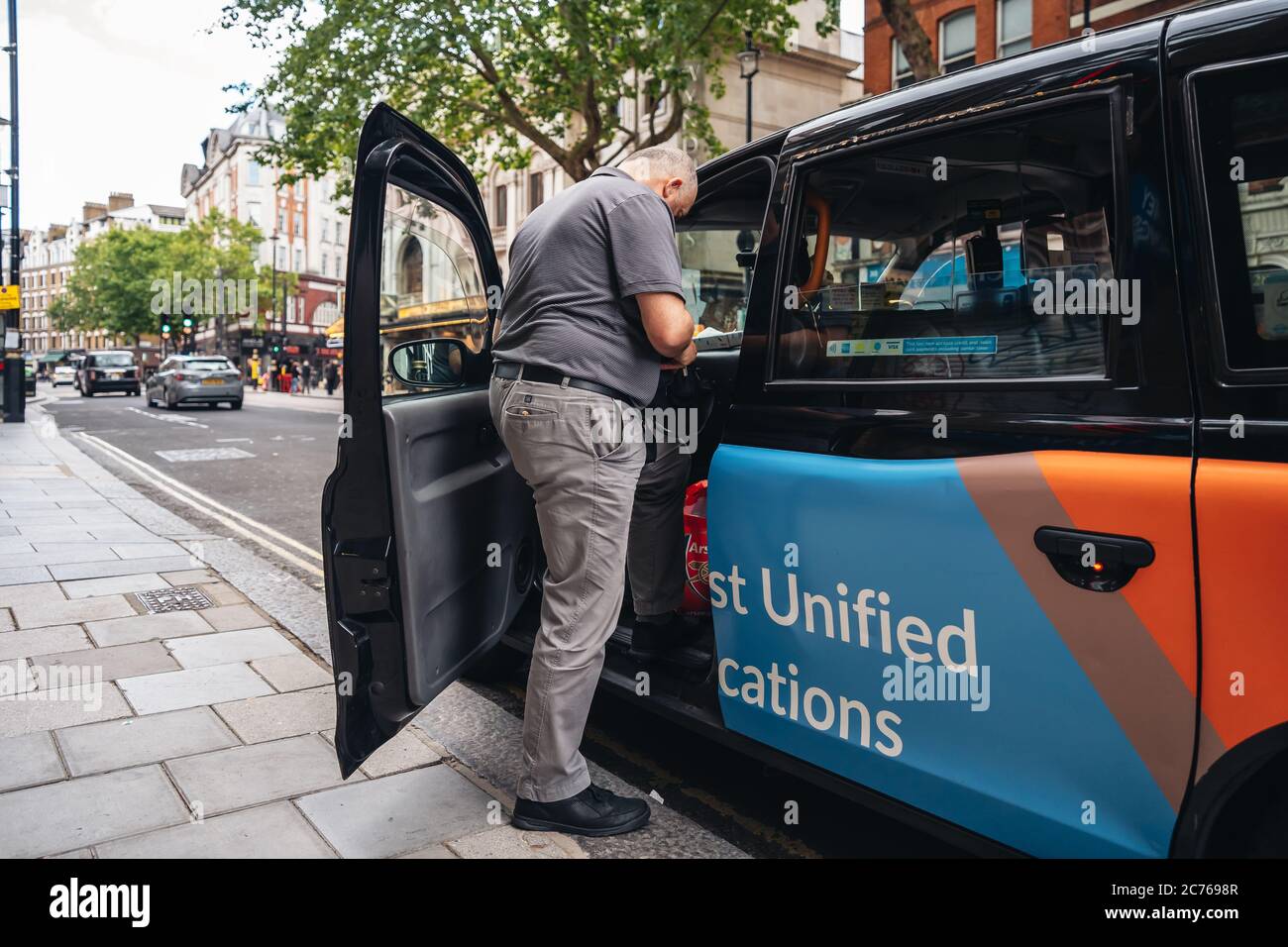 London / UK - 07/11/2020: Taxifahrer, der wieder in sein Auto und zurück zur Arbeit kommt Stockfoto