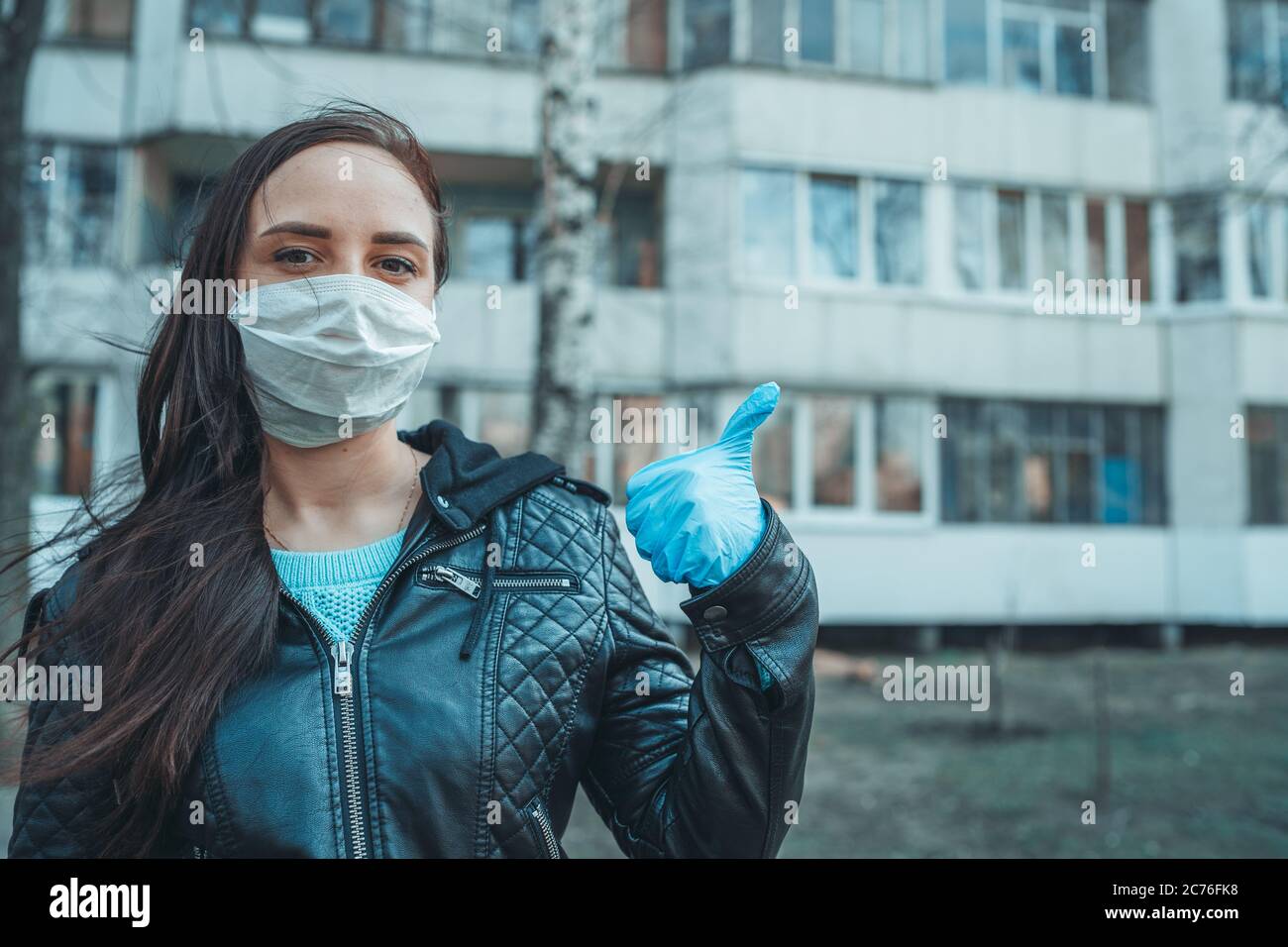 Porträt einer jungen Frau in medizinischer Maske auf ihrem Gesicht auf der Straße stehend. Erwachsene Frau bedeckte ihr Gesicht mit Maske, um sich vor Krankheiten zu schützen. Stockfoto