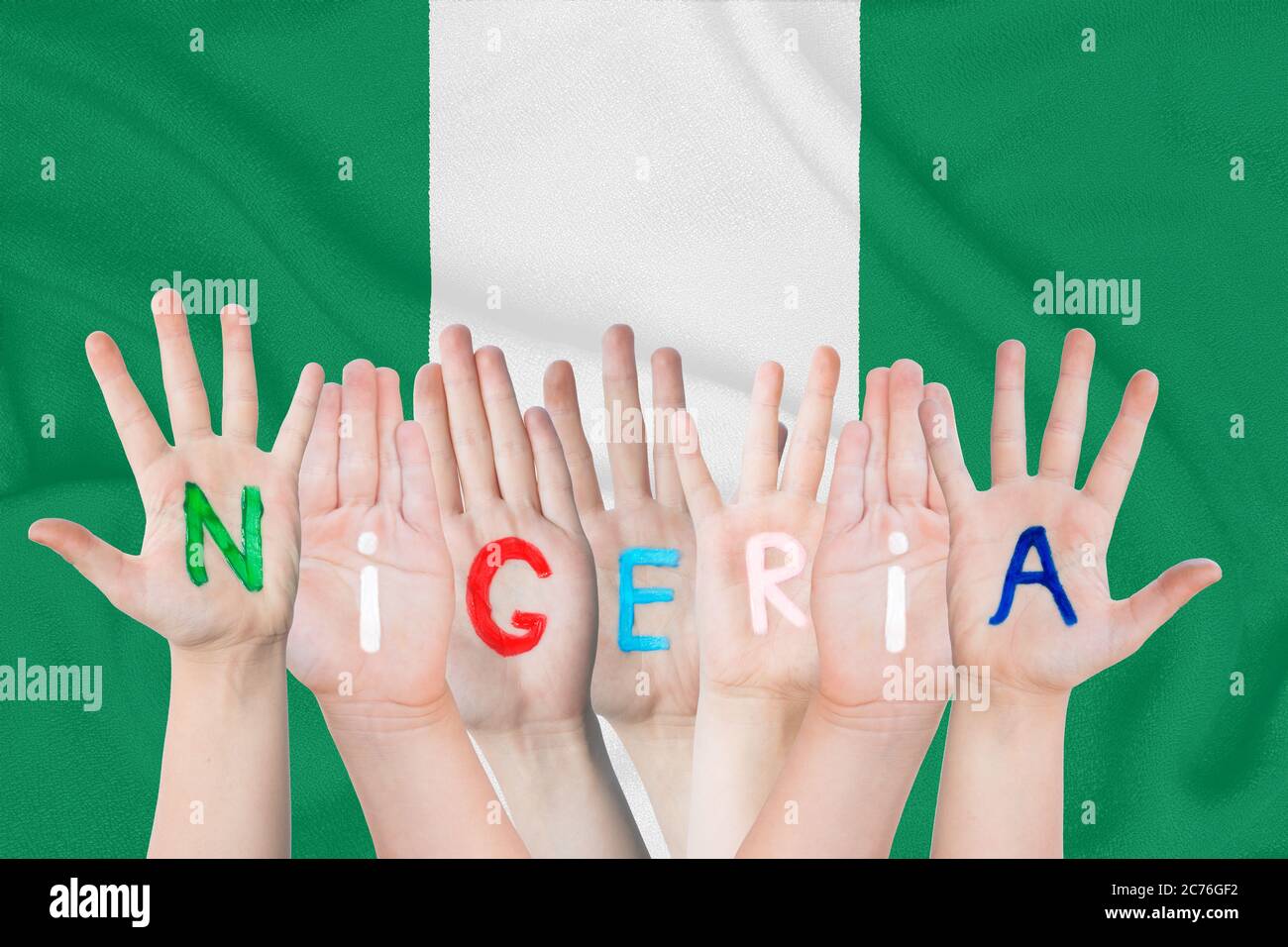 Inschrift Nigeria auf den Kinderhände vor dem Hintergrund einer winkenden Flagge der Nigeria Stockfoto