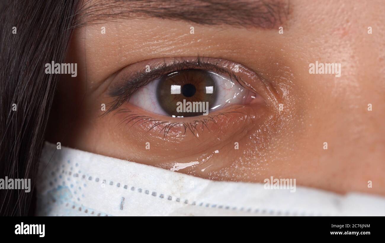 Frau mit medizinischer Maske auf ihrem Gesicht. Nahaufnahme des weinenden Auges der Frau. Konzept der Coronavirus-Epidemie oder Krankheiten. Stockfoto