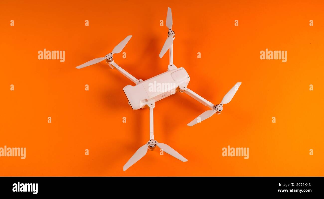 Nahaufnahme der weißen Drohne auf orangefarbenem Hintergrund. Moderne Drohne unbemannte Luftfahrzeug mit Propeller. Stockfoto