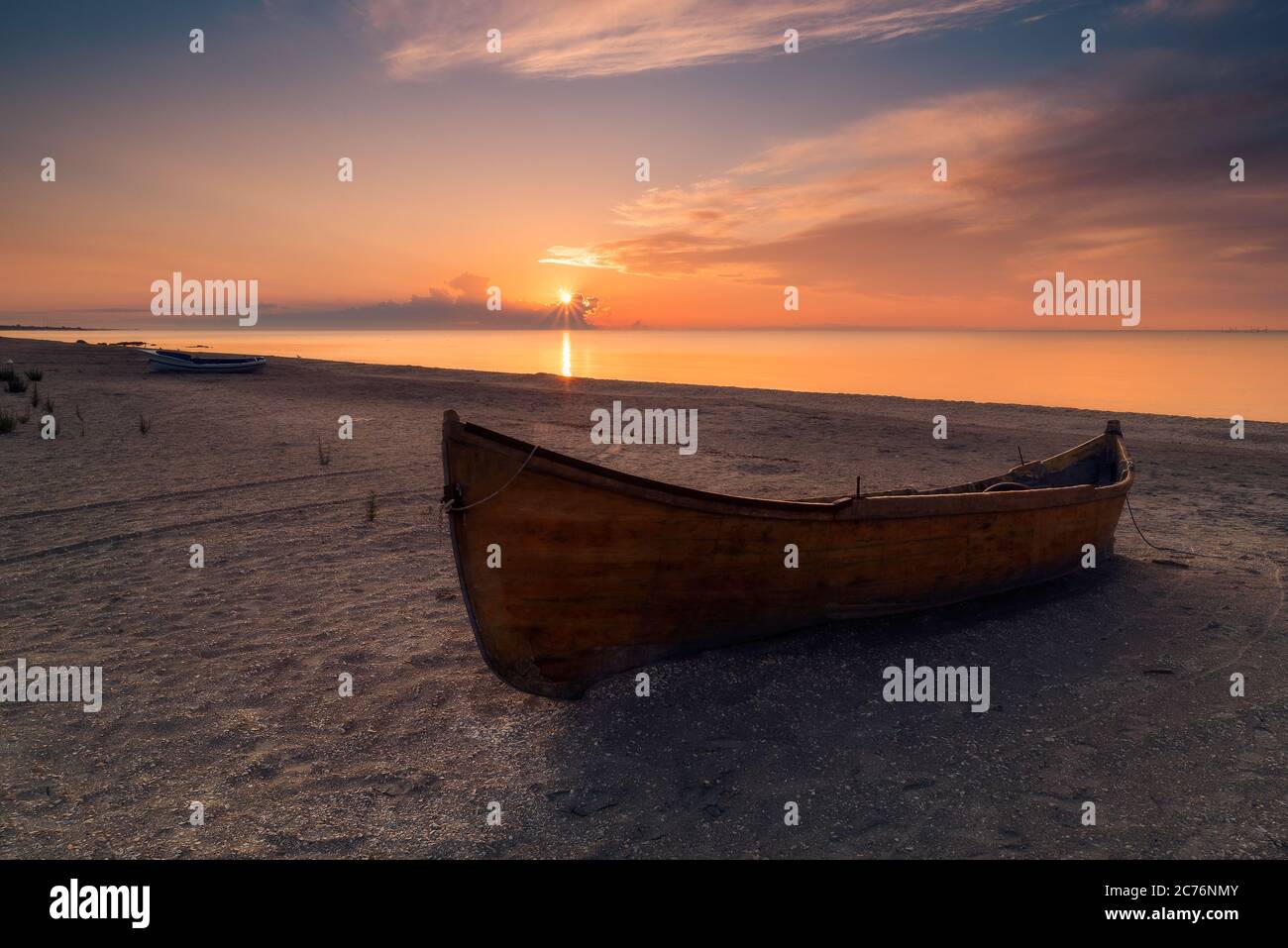 Holzfischerboot, das am Strand bei Sonnenaufgang in Rumänien an der Schwarzmeerküste in Corbu, Constanta County, ruht Stockfoto