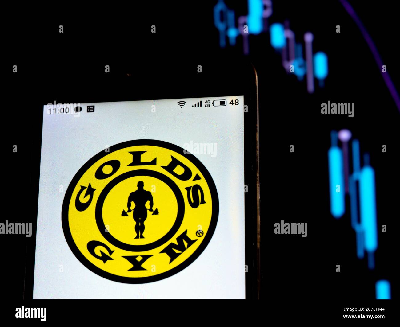 In diesem Foto Illustration Gold Gym Logo auf einem Smartphone auf dem Hintergrund eines Graphen mit fallenden Kurven angezeigt. Laut internationalen Medienberichten während der Coronavirus (COVID-19) Pandemie, Gold Fitness Studio für Insolvenz angemeldet. Stockfoto