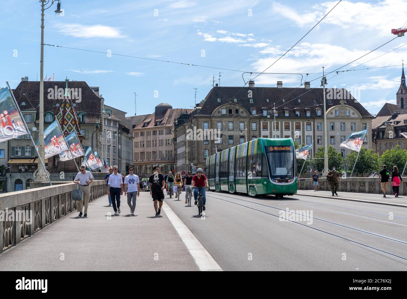 Basel, BL / Schweiz - 8. Juli 2020: Passanten überqueren den Rhein nach Klein Basel mit der Basler Straßenbahn vorbei Stockfoto