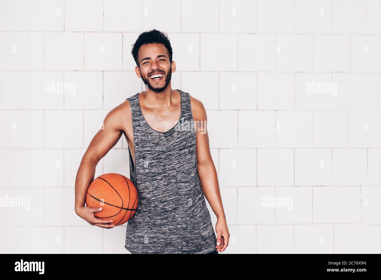 Junger Mann hält einen Basketball, während er lächelt Stockfoto