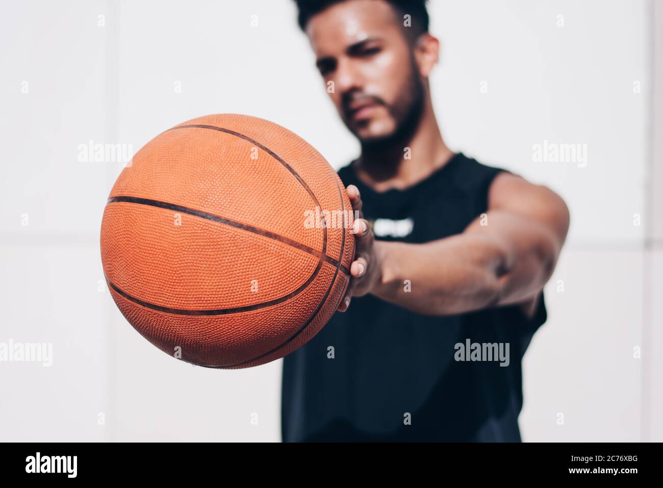 Der junge Mann hält einen Basketball vor der Kamera Stockfoto