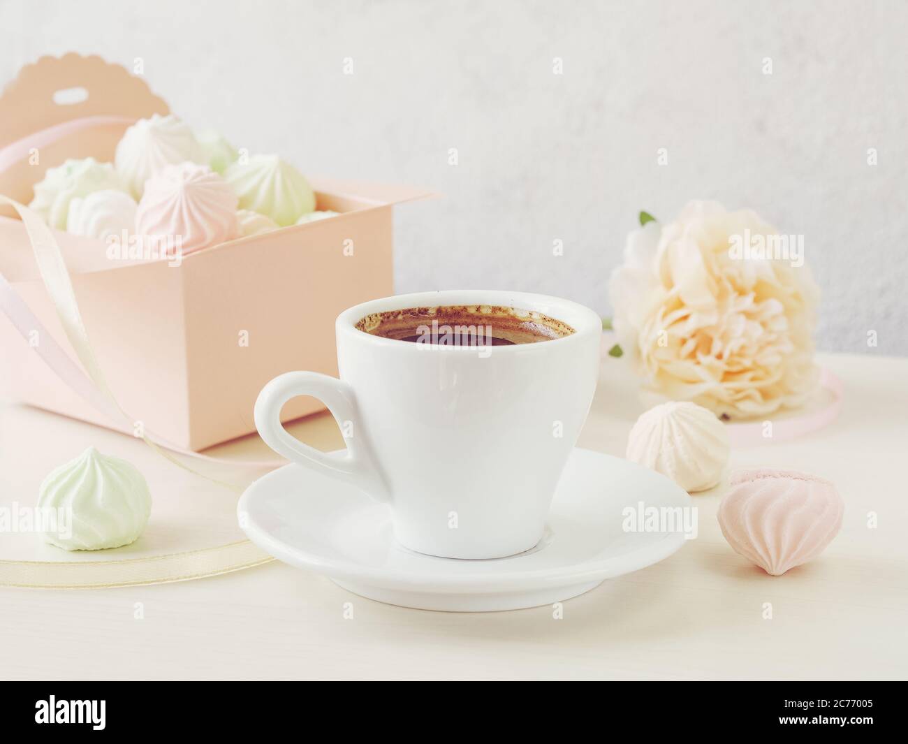 Pastell romantischen Hintergrund mit Kaffee und kleinen Baiseues in einer Box, Blume und Bändern. Stockfoto