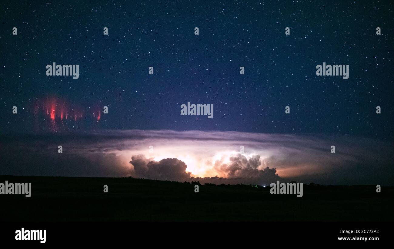 Rot spritzt über einem supercell-Gewitter, während Blitze die Cumulonimbuswolke unten in der Nähe von Hay Springs, Nebraska, erhellen Stockfoto