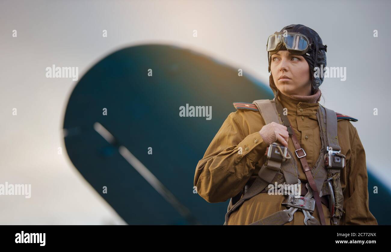 Eine junge Pilotin in Uniform der sowjetischen Armee Piloten während des Zweiten Weltkriegs Militär-Shirt mit Schulterriemen eines Major, Fallschirm, Flug helme Stockfoto