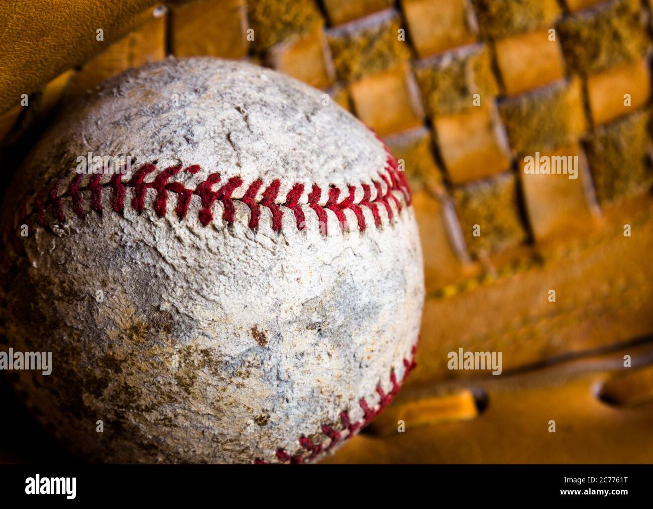 Nahaufnahme des Baseballs in einem Handschuh. Der Ball ist alt und beschädigt, gut mit Abrieb, Flecken und Nähen an Stellen verwendet. Stockfoto
