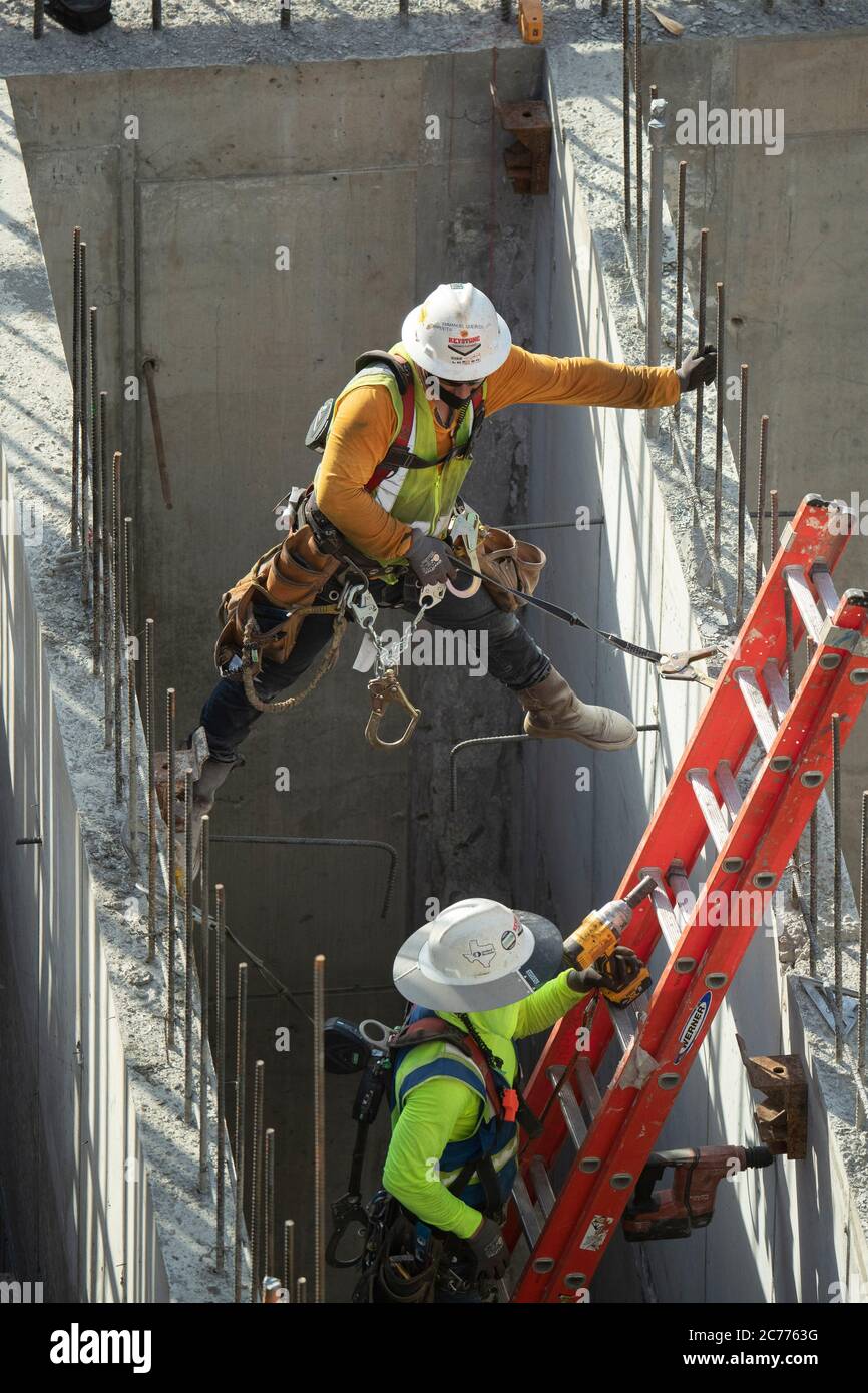 Austin, TX USA 14. Juli 2020: Bauarbeiter Emmanuel Quevedo bereitet während einer achtstündigen Schicht bei der 105-Grad-Hitze in Texas einen Aufzugsschacht für zusätzliche Versteifungen vor. Die Crews befinden sich im zweiten Stock eines geplanten 53-stöckigen Gebäudes, um Vorkehrungen gegen die Coronavirus-Pandemie zu treffen. Stockfoto