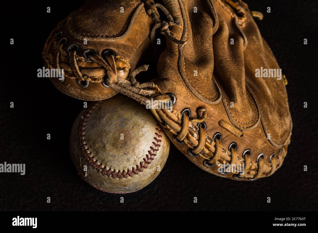 Abgenutzte Fänger Fäustling auf einem abgetragenen bis verfleckten alten Baseball ruhen Stockfoto