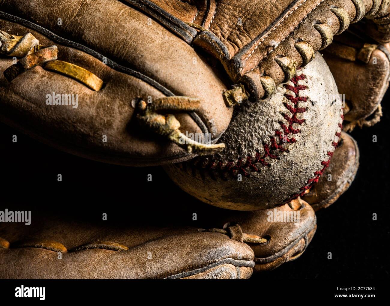 Baseballhandschuh hält einen abgewetzten alten Baseball. Stockfoto