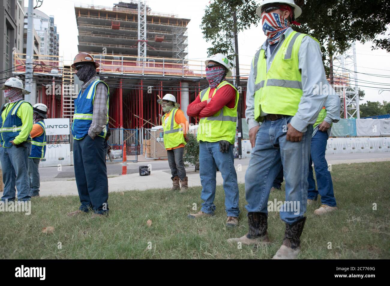 Austin, TX USA 14. Juli 2020: Bauarbeiter hören sich Sicherheitsunterweisungen an, während sie sich auf eine achtstündige Schicht in der 105-Grad-Hitze von Texas vorbereiten. Die Crews befinden sich im zweiten Stock eines geplanten 53-stöckigen Gebäudes, um Vorkehrungen gegen die Coronavirus-Pandemie zu treffen. Stockfoto