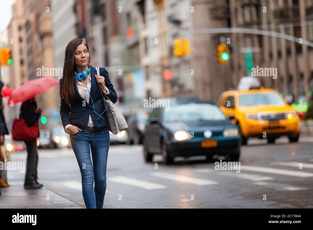 Junge asiatische professionelle Frau zu Fuß nach Hause pendeln von der Arbeit in New York City Street. Urban People Lifestyle Pendler in NYC Verkehr regen Tag Stockfoto