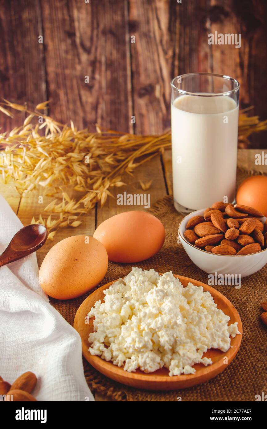 Rustikale hausgemachte Protein ausgewogene Ernährung Lebensmittel. Hüttenkäse, Eier, Nüsse und Milch auf einem Holzhintergrund. Vertikales Foto Stockfoto
