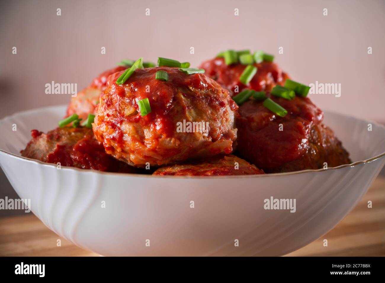 Fleischbällchen mit Tomatensauce und Kräutern. Appetitliche Fleischbällchen mit grünen Zwiebeln aus der Nähe Stockfoto
