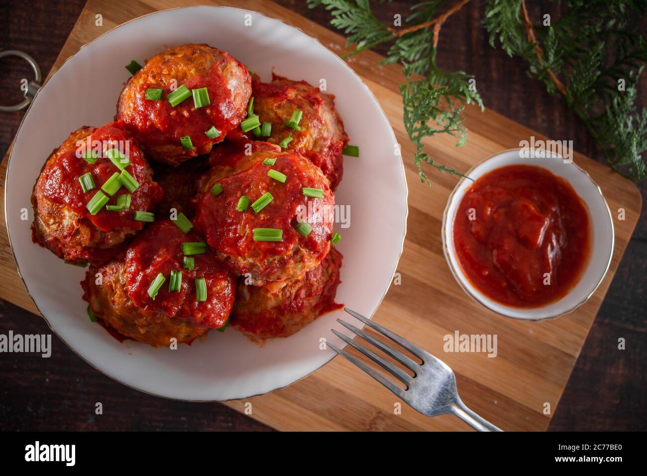 Fleischbällchen mit Tomatensauce und Kräutern. Appetitliche Fleischbällchen aus Öko-Produkten auf Holzhintergrund Stockfoto