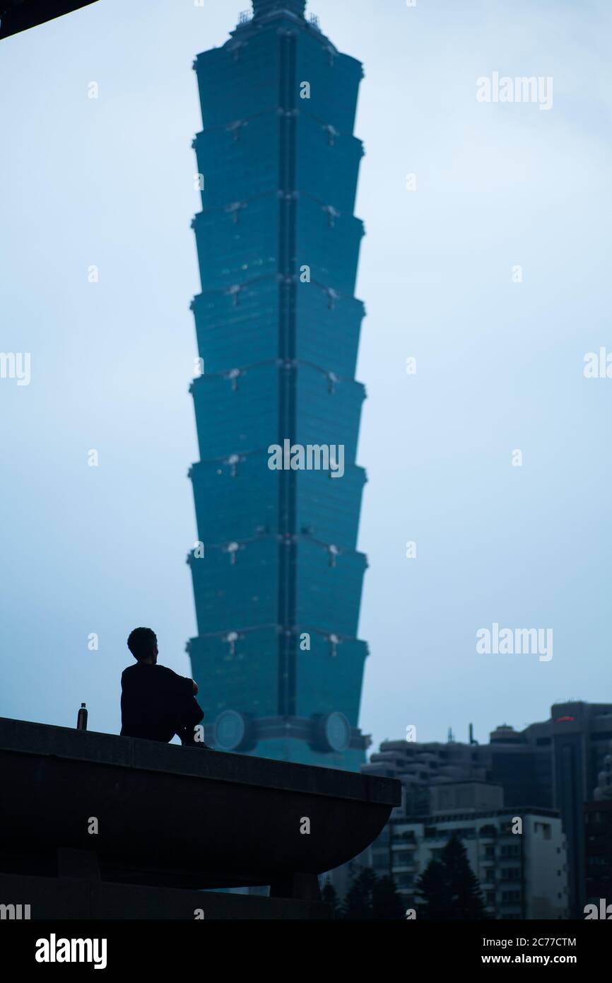 Vertikale Ansicht. Ein Mann, der sich hinsetzt und Taipeh 101, Taipeh, Taiwan anschaut Stockfoto