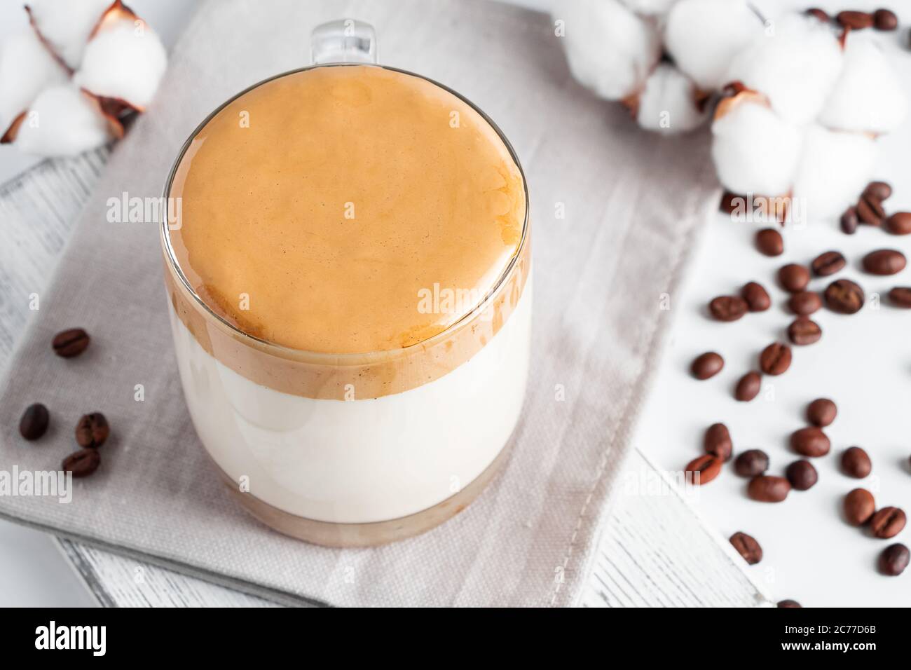 Trending koreanischen Getränk - Dalgona Kaffee. Ein Glas Eismilch mit süßem Schlagschaum auf hellem Hintergrund. Stockfoto