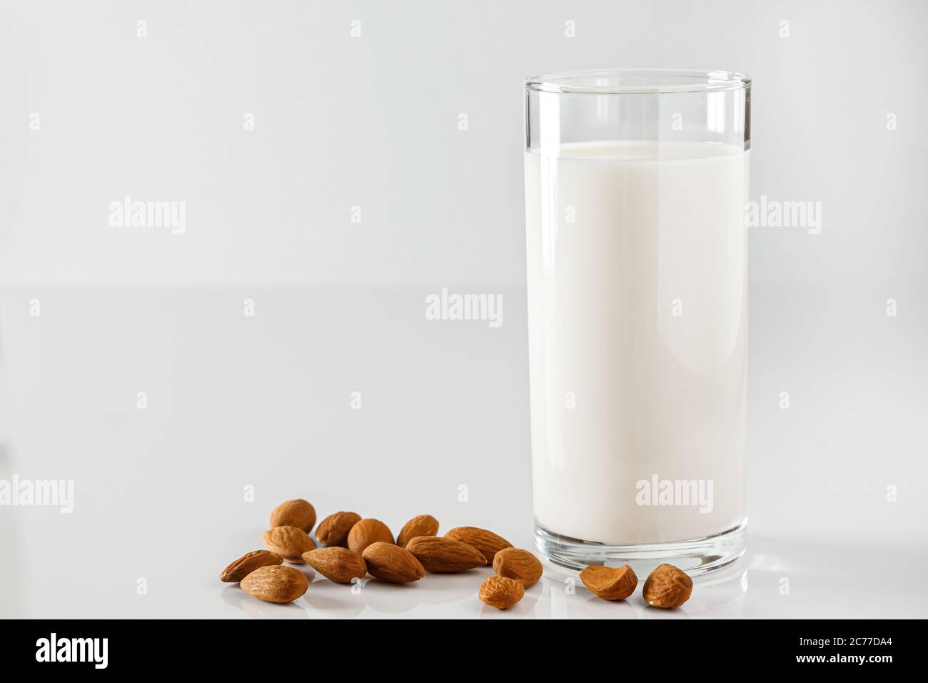 Ein Glas Mandelmilch auf weißem Hintergrund. Laktosefreie pflanzliche Ernährung Milch. Glutenfreies Mandelgetränk auf blauem Hintergrund. Super Essen - EIN Glas Stockfoto