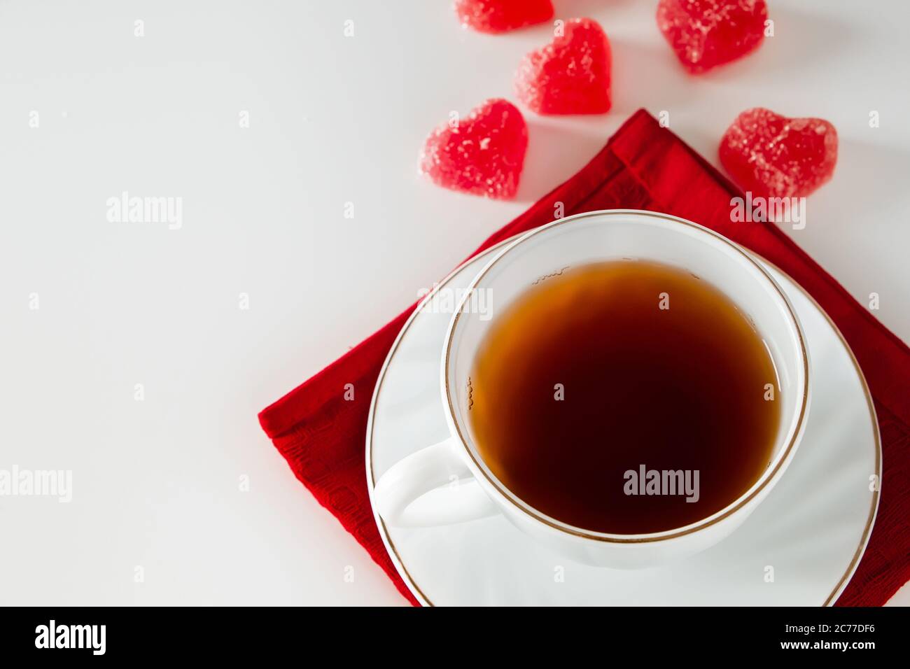 Tasse Tee auf weißem Hintergrund und rote Marmelade in Form eines Herzens. Das Konzept des Rauchs aus einer Tasse in Form eines Herzens, ein Symbol der Liebenden Stockfoto