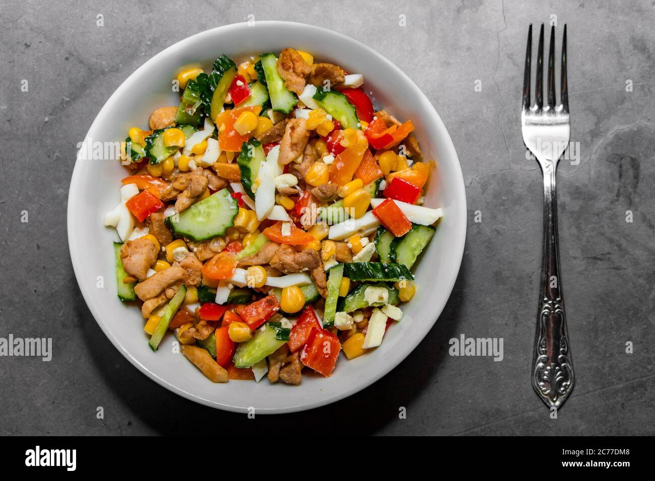 Heller Gemüsesalat mit Huhn auf grauem Betongrund. Machen Sie einen leckeren Salat für eine gesunde Ernährung. Gemüsesalat für die richtige Ernährung i Stockfoto