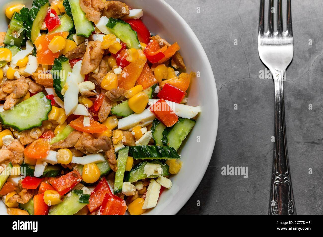 Heller Gemüsesalat mit Huhn auf grauem Betongrund. Machen Sie einen leckeren Salat für eine gesunde Ernährung. Gemüsesalat für die richtige Ernährung i Stockfoto